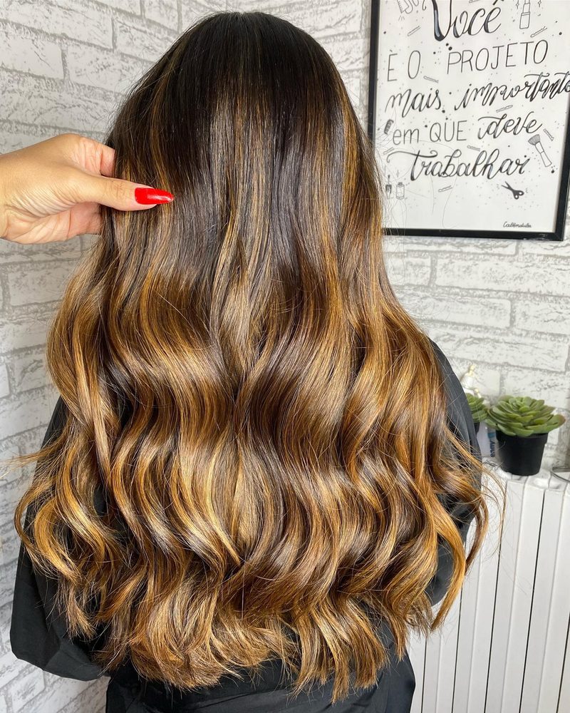 Cabelo castanho com mechas caramelo em ondas, visto de costas