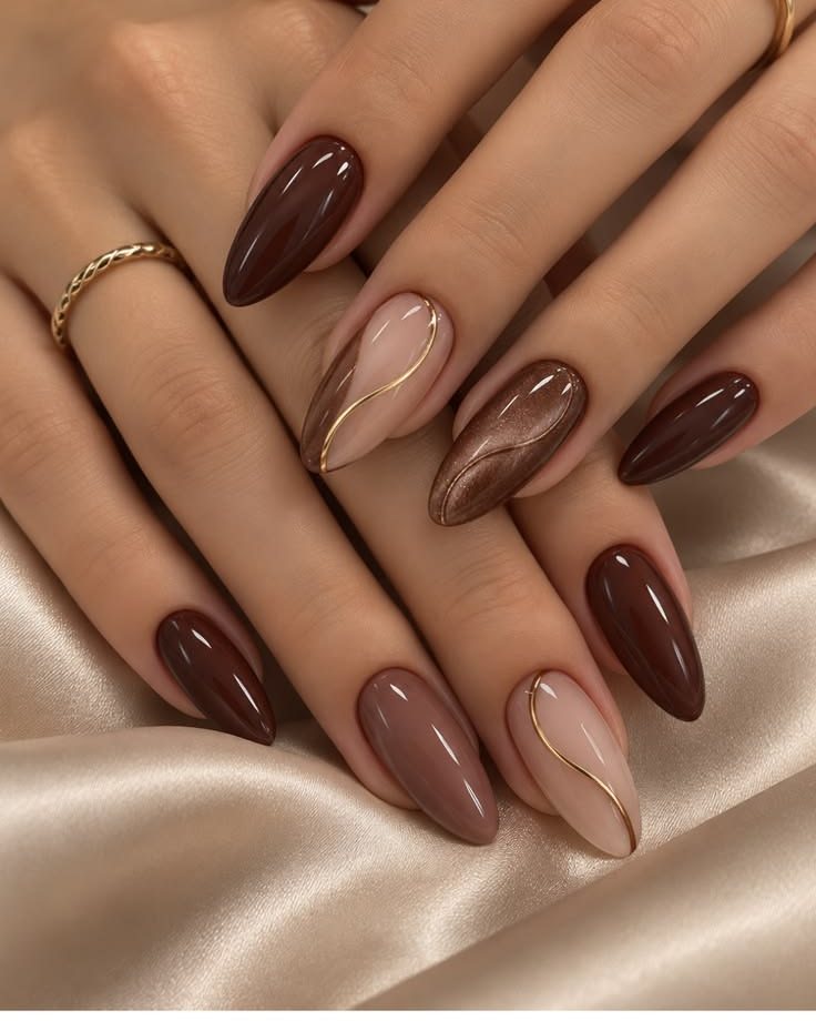 Unhas amendoadas em tons de marrom e nude com filete dourado