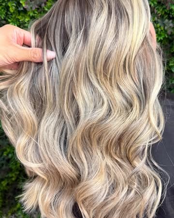 Cabelo loiro em ondas, visto de costas, na parede verde do salão